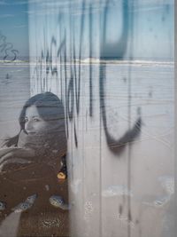 Double exposure image of woman sitting by wall at beach