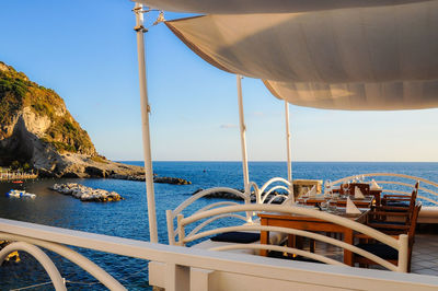 Table and chairs at restaurant against sea