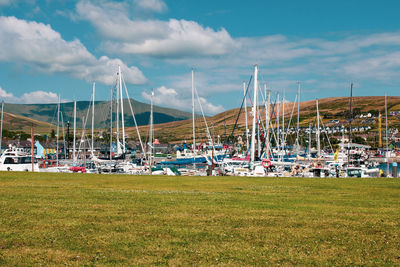 Sailboats moored on field against sky