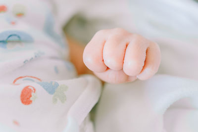 Close-up of baby fist on bed