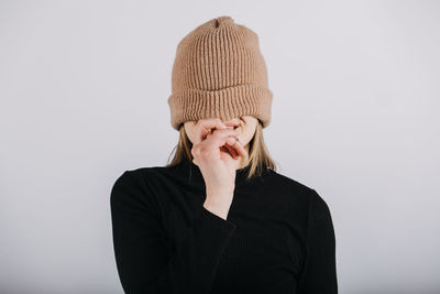 Unaltered candid emotional portrait of young happy blonde long hair woman covering eyes with brown