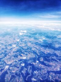 Aerial view of sea and landscape against blue sky