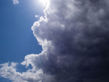 Low angle view of sunlight streaming through clouds