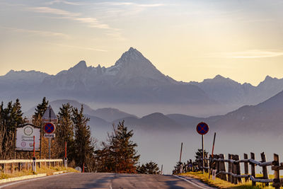 Road leading towards mountains against sky during sunset