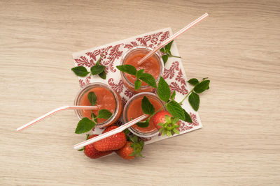 Top view of several strawberry milkshakes with wooden background