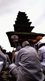 Rear view of people at temple against sky