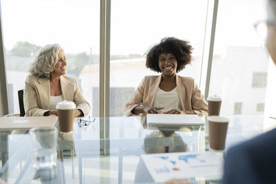 Senior businesswoman looking at colleague discussing in meeting at office