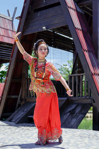 Portrait of young woman standing against building