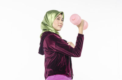 Side view of woman standing against pink background