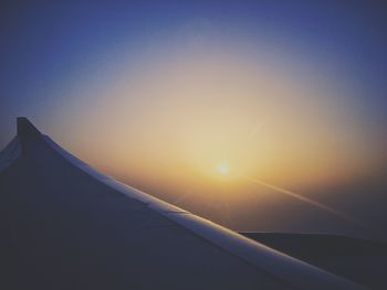 Airplane wing against clear sky during sunset