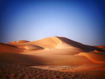 Scenic view of desert against clear blue sky