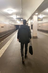 Rear view of man walking on subway station