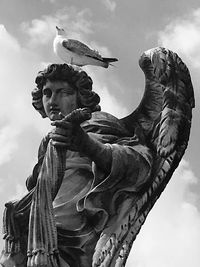 Low angle view of angel statue against cloudy sky