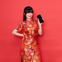Young woman smiling against red background