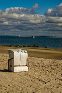 Hooded beach chair on shore against sky