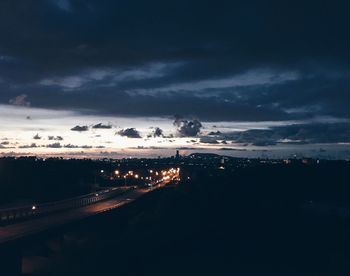 Illuminated cityscape against cloudy sky