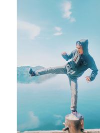 Young man standing by sea against sky