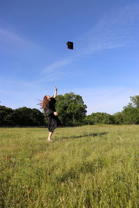 Graduate throwing cap in a field up im the air 