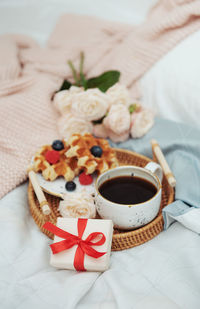 Romantic breakfast with coffee, waffles, gift box and rose flowers.