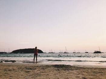 Man standing on beach against clear sky during sunset