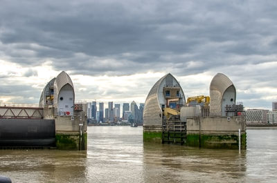 View of buildings at waterfront against cloudy sky