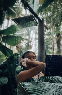 Woman taking shower amidst plants