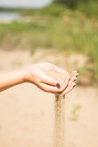 Midsection of woman holding stick on sand