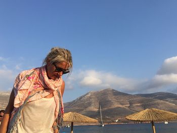 Senior woman standing by mountains against sky