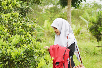 Side view of woman standing by plants on land