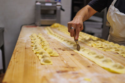 Preparing italian stuffed tortelli on a long wooden table.