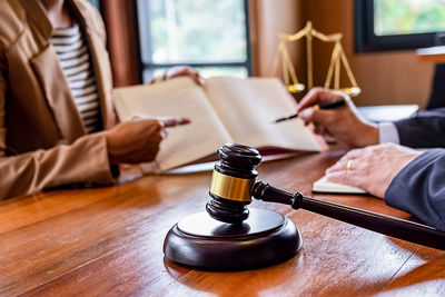 Midsection of woman discussing with judge over book at desk