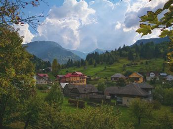 Houses on field by mountains against sky