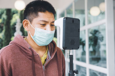 Close-up of man wearing mask checking temperature