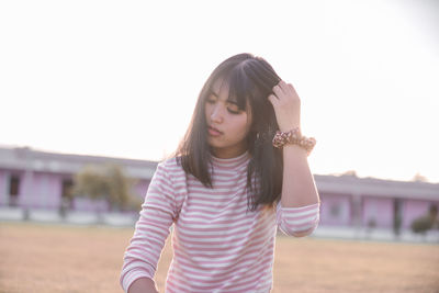 Beautiful young woman standing against clear sky