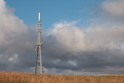 Low angle view of communications tower on field against sky