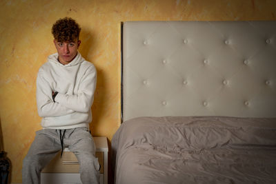 Portrait of young woman sitting on bed at home