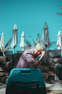 Rear view of man sitting against blue sky