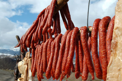 Close-up of sausages hanging on bamboo for drying against sky outdoors