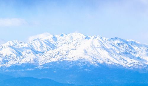 Scenic view of snow covered mountains against blue sky