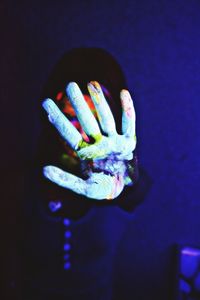 Close-up of human hand against illuminated blue background