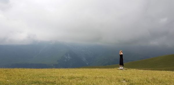 Rear view of man standing on field against sky