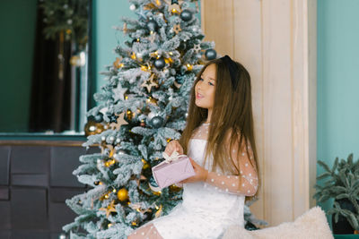 A lovely girl of seven is enjoying the holiday season at home with a christmas tree and gifts person