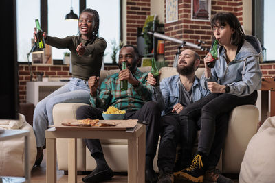 Friends using smart phones while sitting on sofa at restaurant