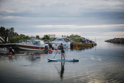 Woman paddleboarding, boats inn background