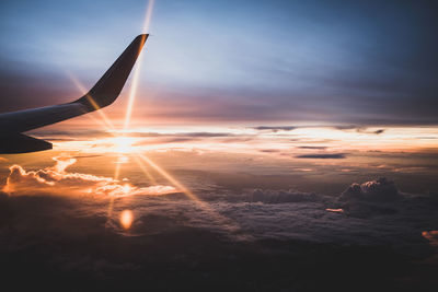 Airplane wing against sky during sunset