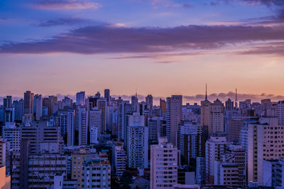 Modern buildings in city against sky during sunset