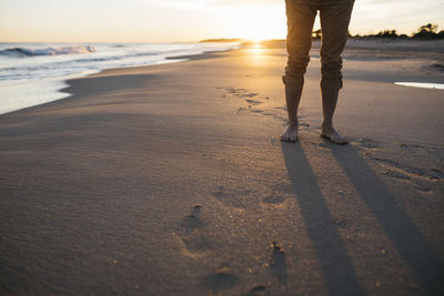 Low section of man standing at beach