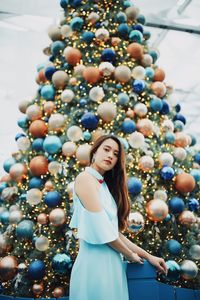 Portrait of smiling young woman standing by christmas tree outdoors