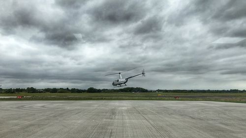 Airplane flying over airport runway against sky