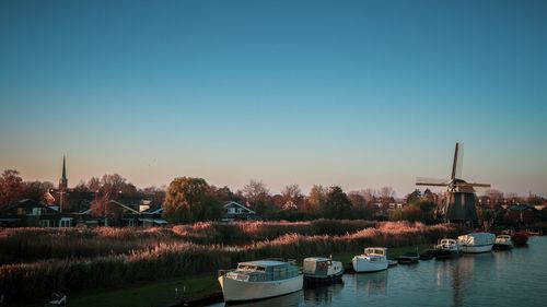 Sailboats moored in lake against clear sky